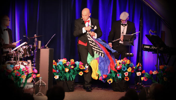 Wolf Fisher präsentiert als Cabaret Conférencier auf der Bühne eine magische Zaubershow mit hervorgezauberten Tüchern in der Hand.